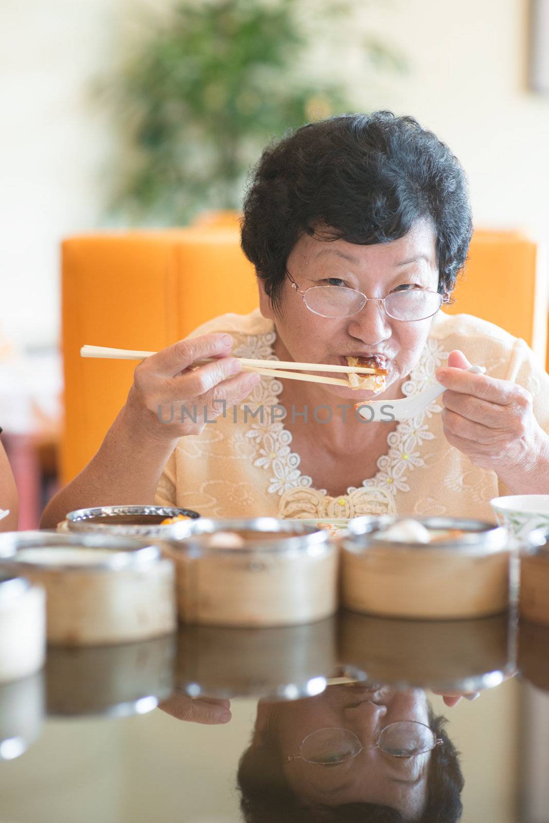Happy 60s Senior Asian Woman dining at restaurant