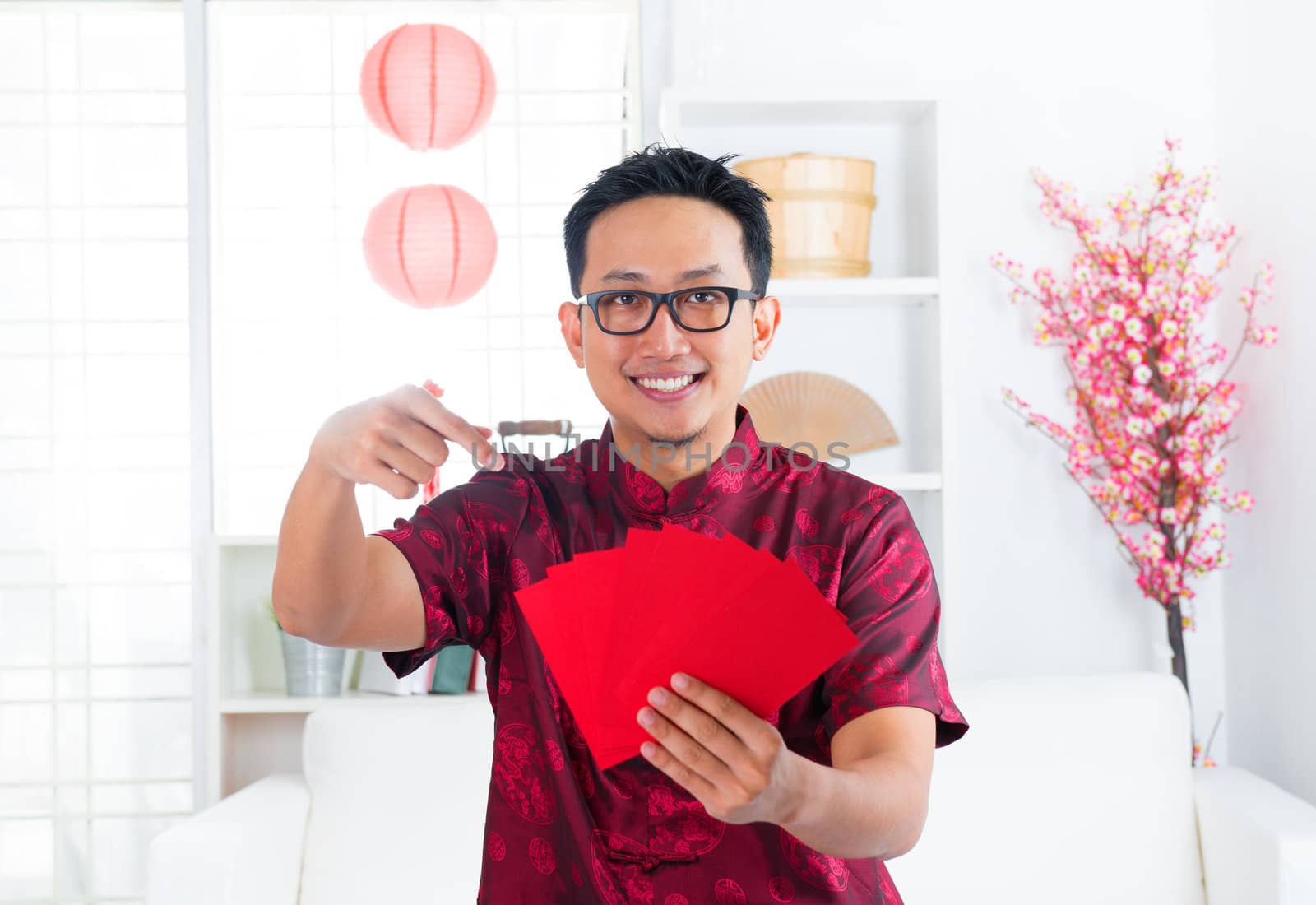 Southeast Asian Chinese man pointing at many red packets / ang pow indoors