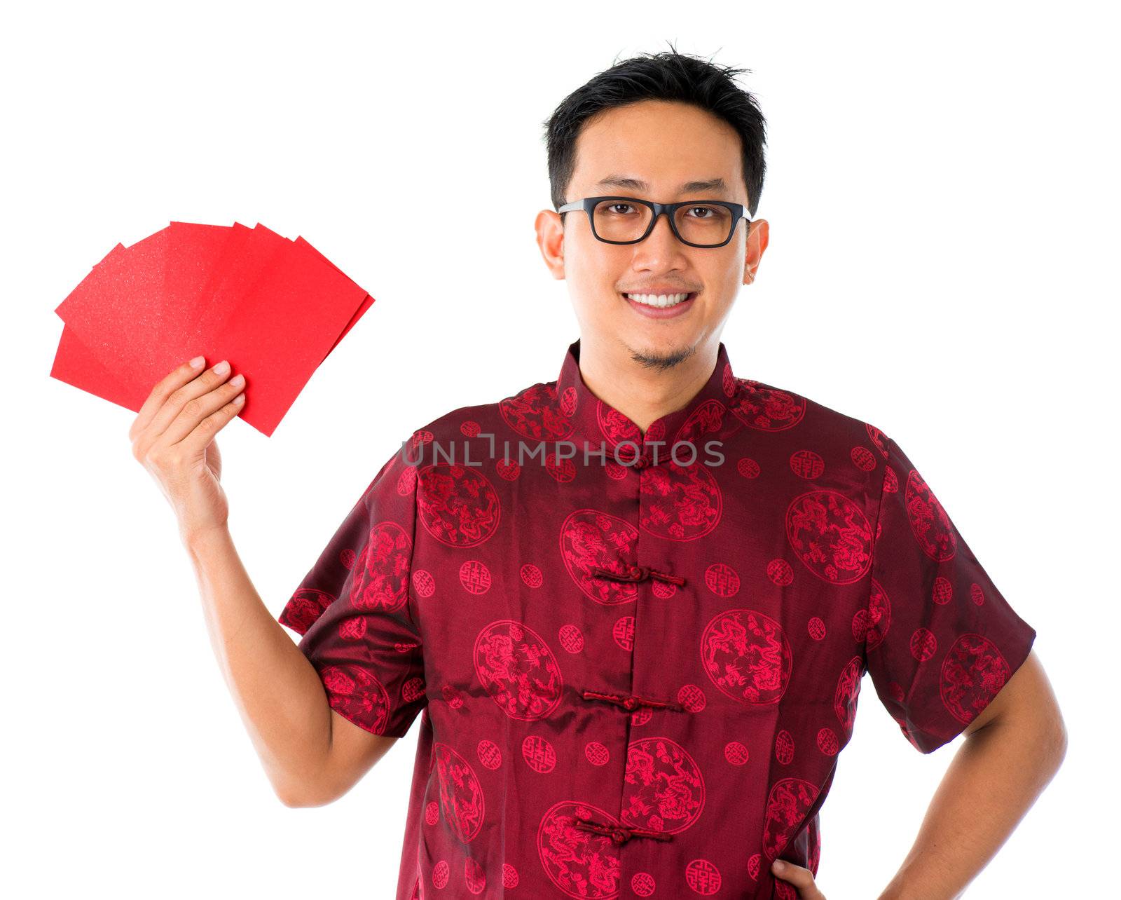 Southeast Asian male in cheongsam hands holding red packets / ang pow , isolated on white background.