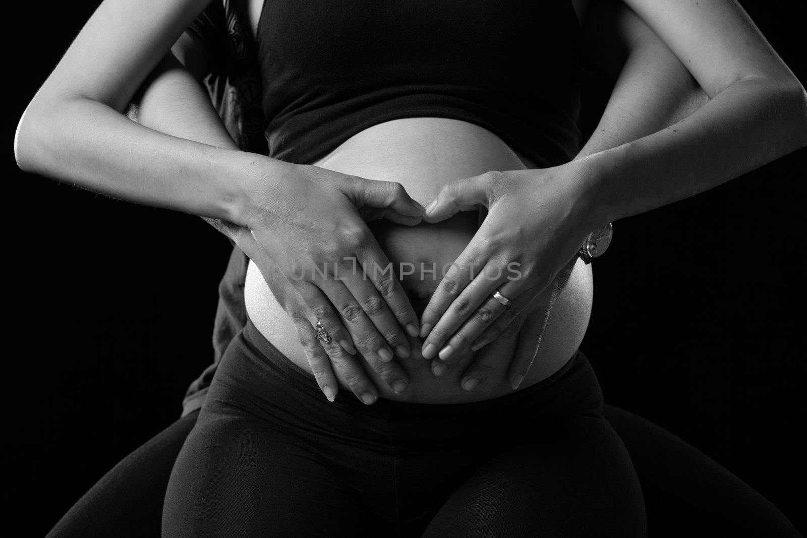 Hands of father and mother. The splice is shaped like a heart on her stomach.