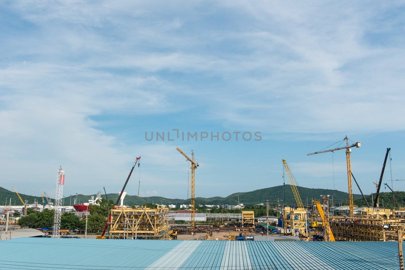 Large construction site with multiple metal cranes, taken on a sunny day