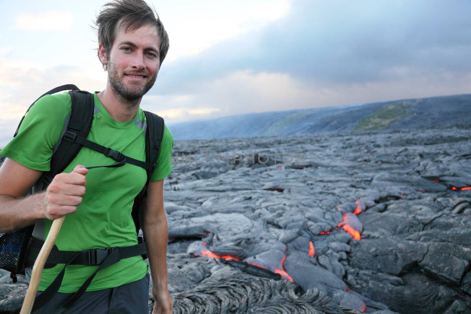 Hawaii hiker hiking by flowing lava from Kilauea volcano around Hawaii volcanoes national park, USA. Young caucasian man..