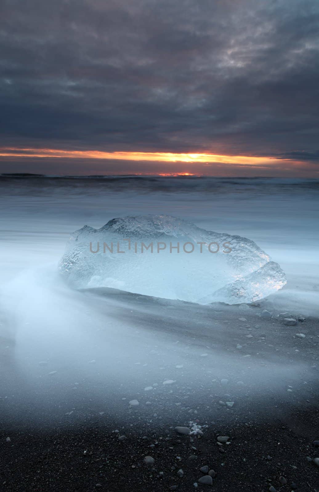 Ice on vocanic black sand iceland beach at sunset