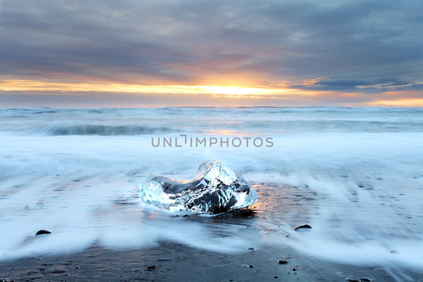 Ice on vocanic black sand iceland beach at sunset