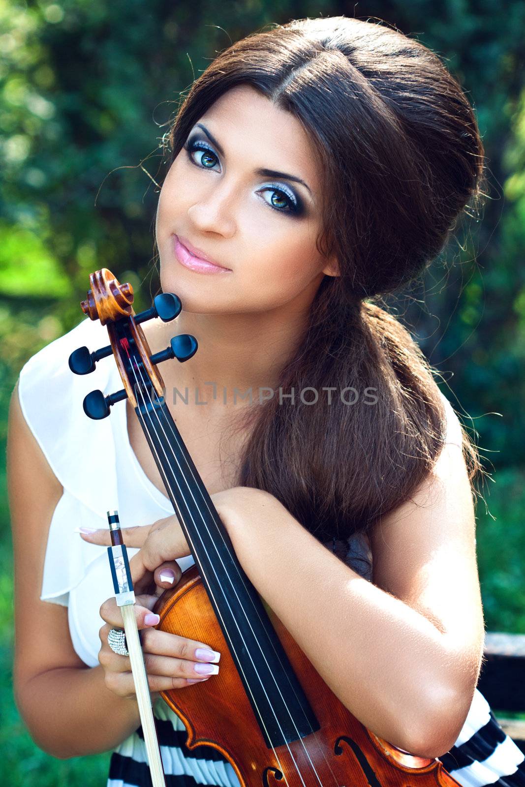 A portraite or a pretty violinist in the park 