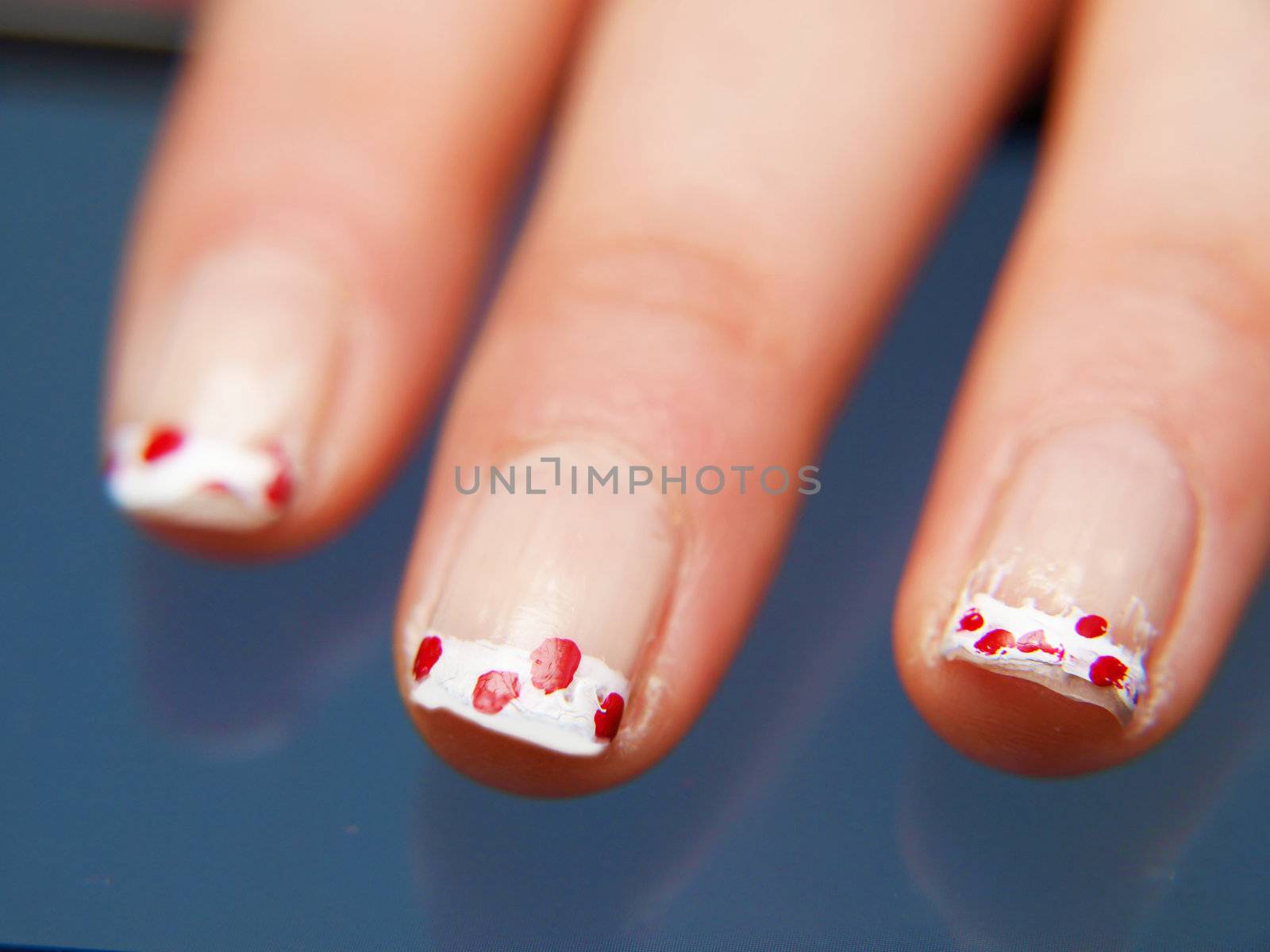 Close up of female hands with red and white manicure by Arvebettum