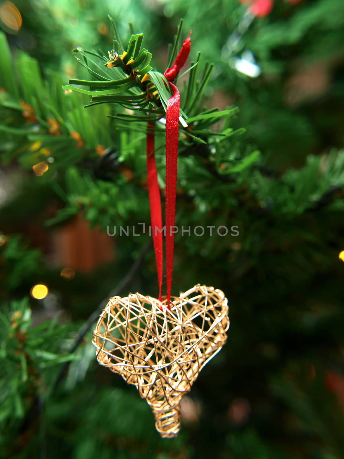 Golden heart ornament hanging on a Christmas tree by Arvebettum