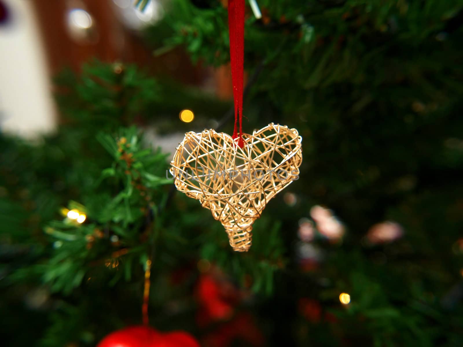 Golden heart ornament hanging on a Christmas tree by Arvebettum