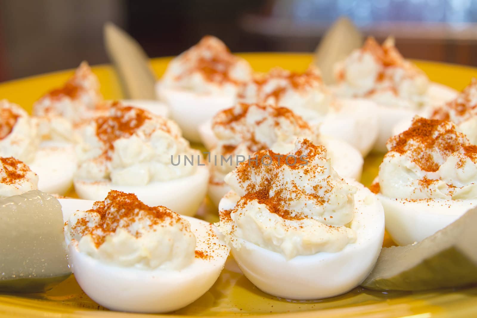 Plate of Deviled Eggs Hors D'Oeuvre sprinkled with Paprika Spice and Pickles Closeup