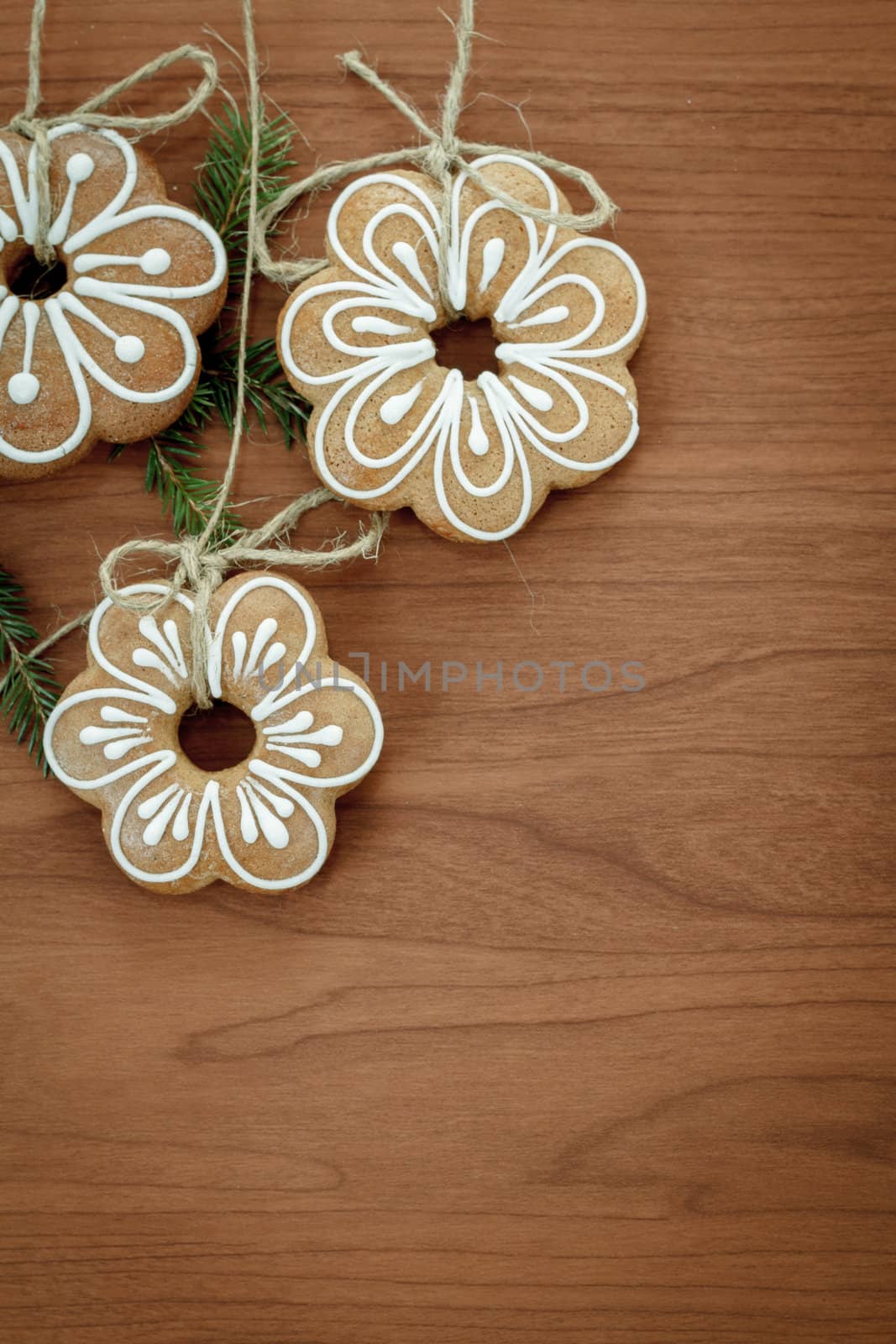 Gingerbread cookies with twig hanging over wooden background