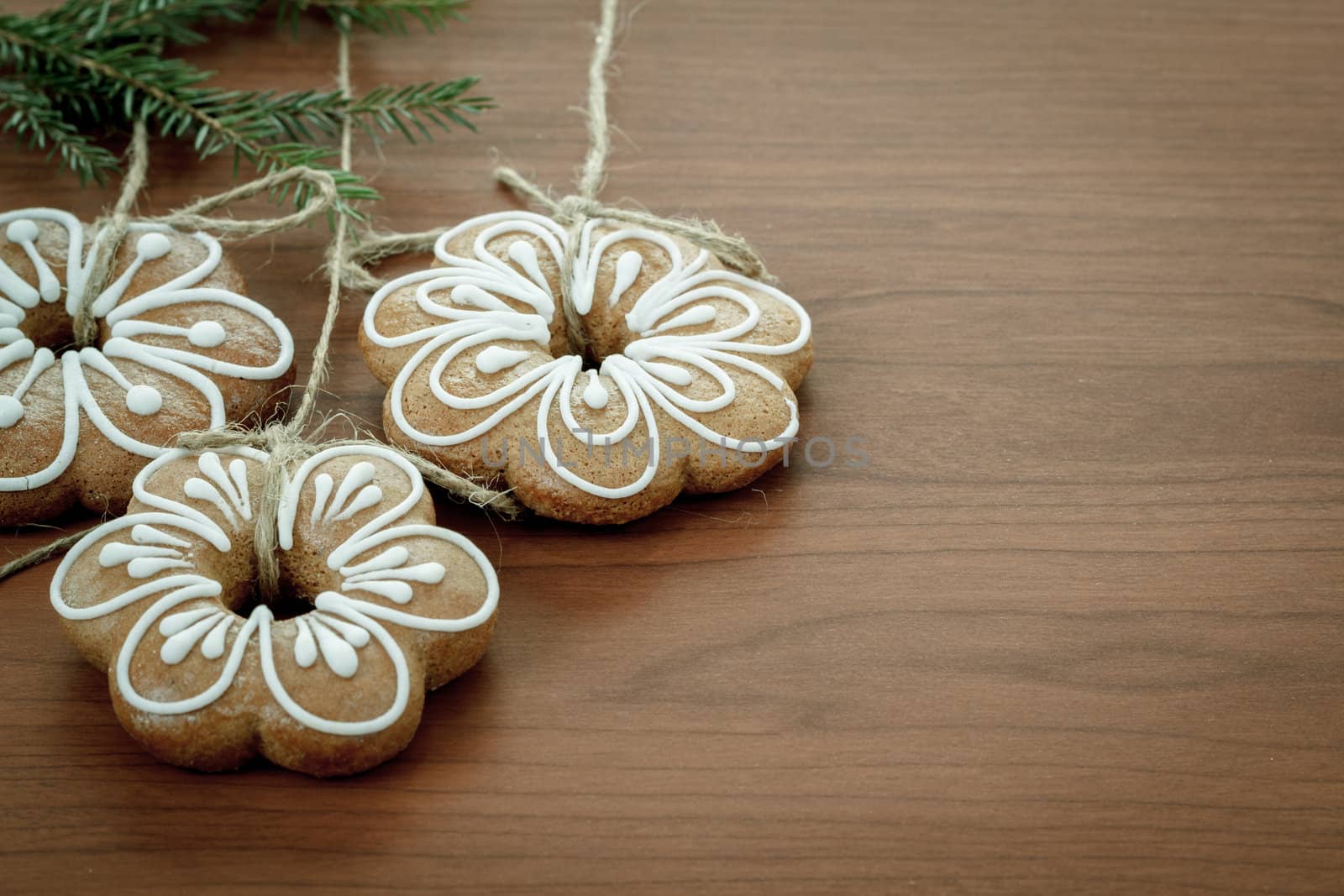Gingerbread cookies with twig hanging over wooden background