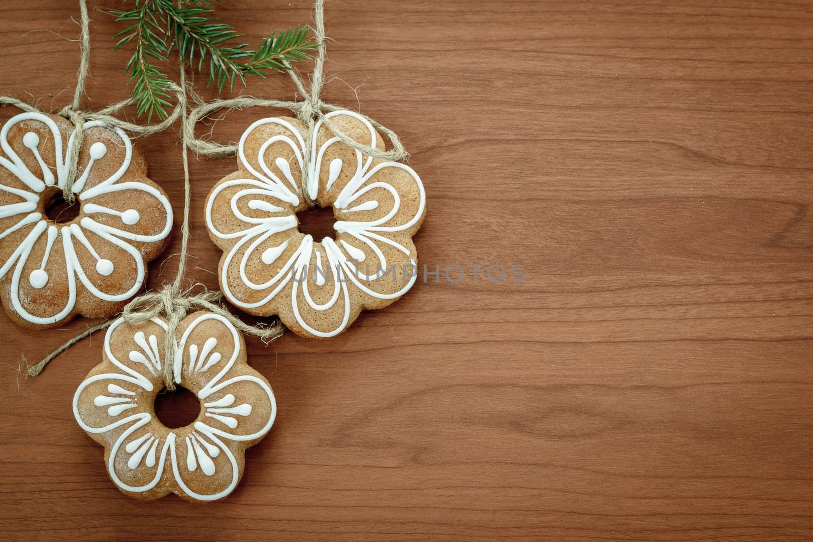 Gingerbread cookies with twig hanging over wooden background