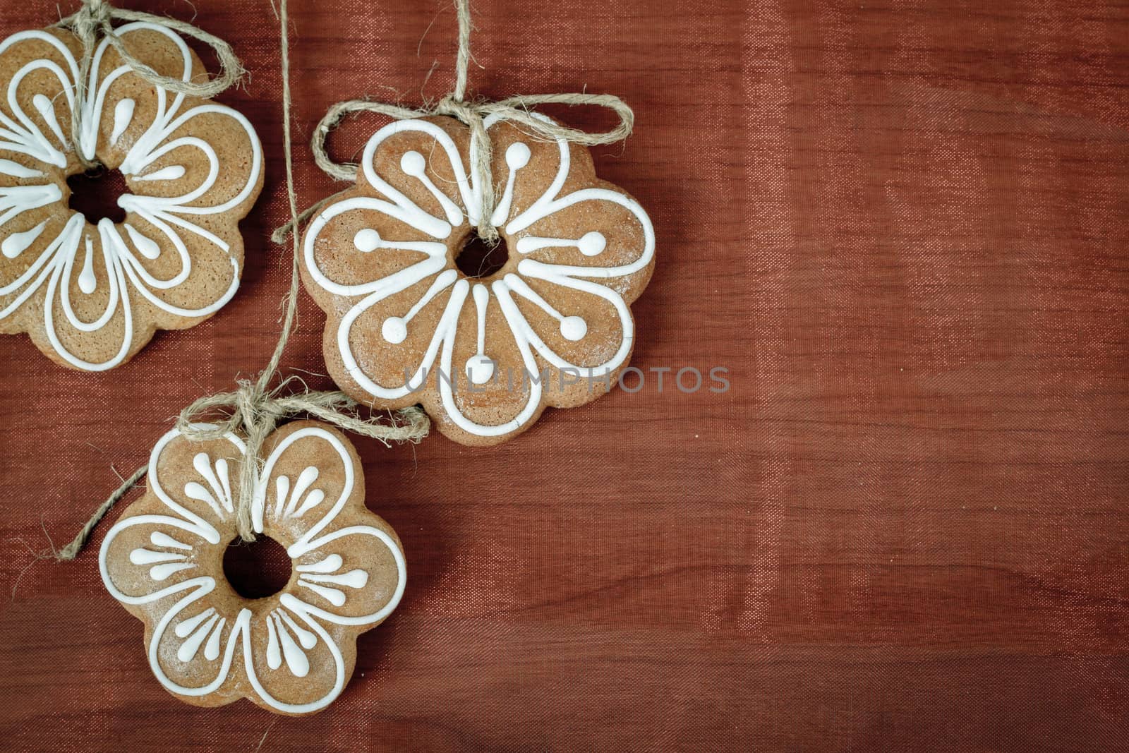 Gingerbread cookies with twig hanging over wooden background