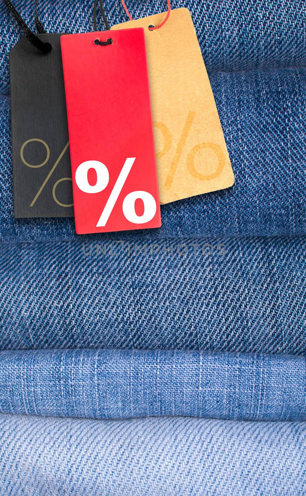 Sale Tags With Percentage Symbol on Stack of Blue Jeans