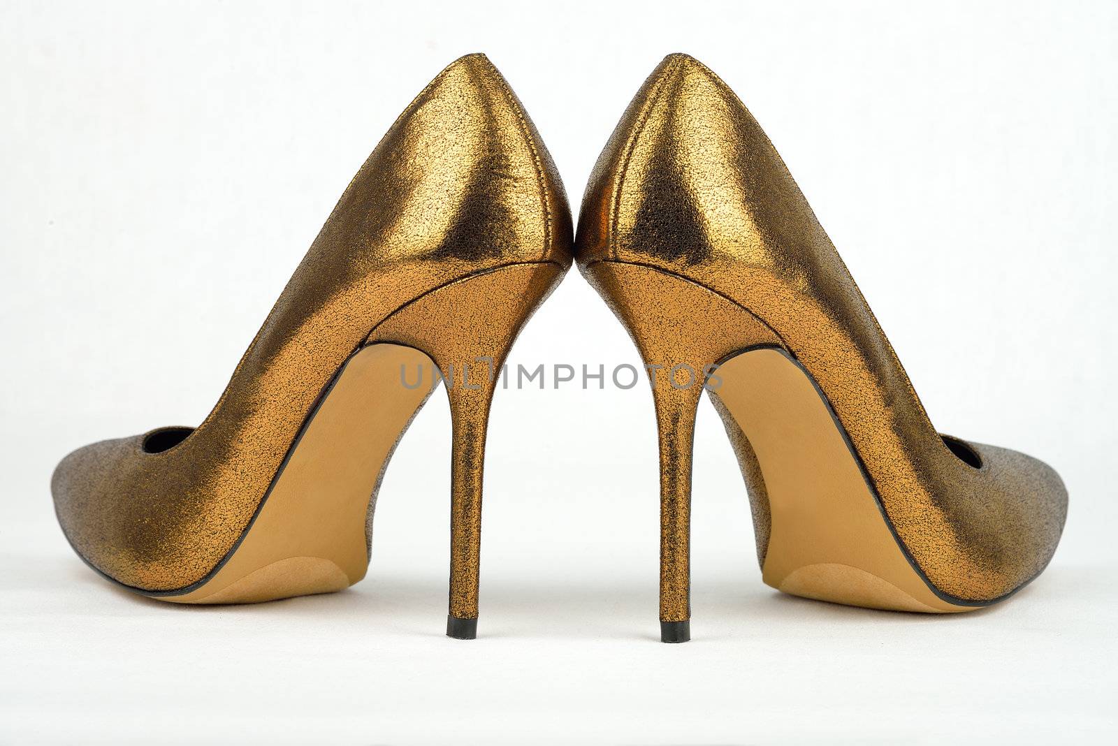 Pair of golden colored High Heel shoes against white background