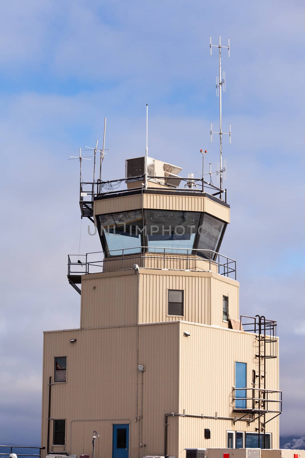 Small airport air traffic control tower with huge glass windows and antennas mounted on roof