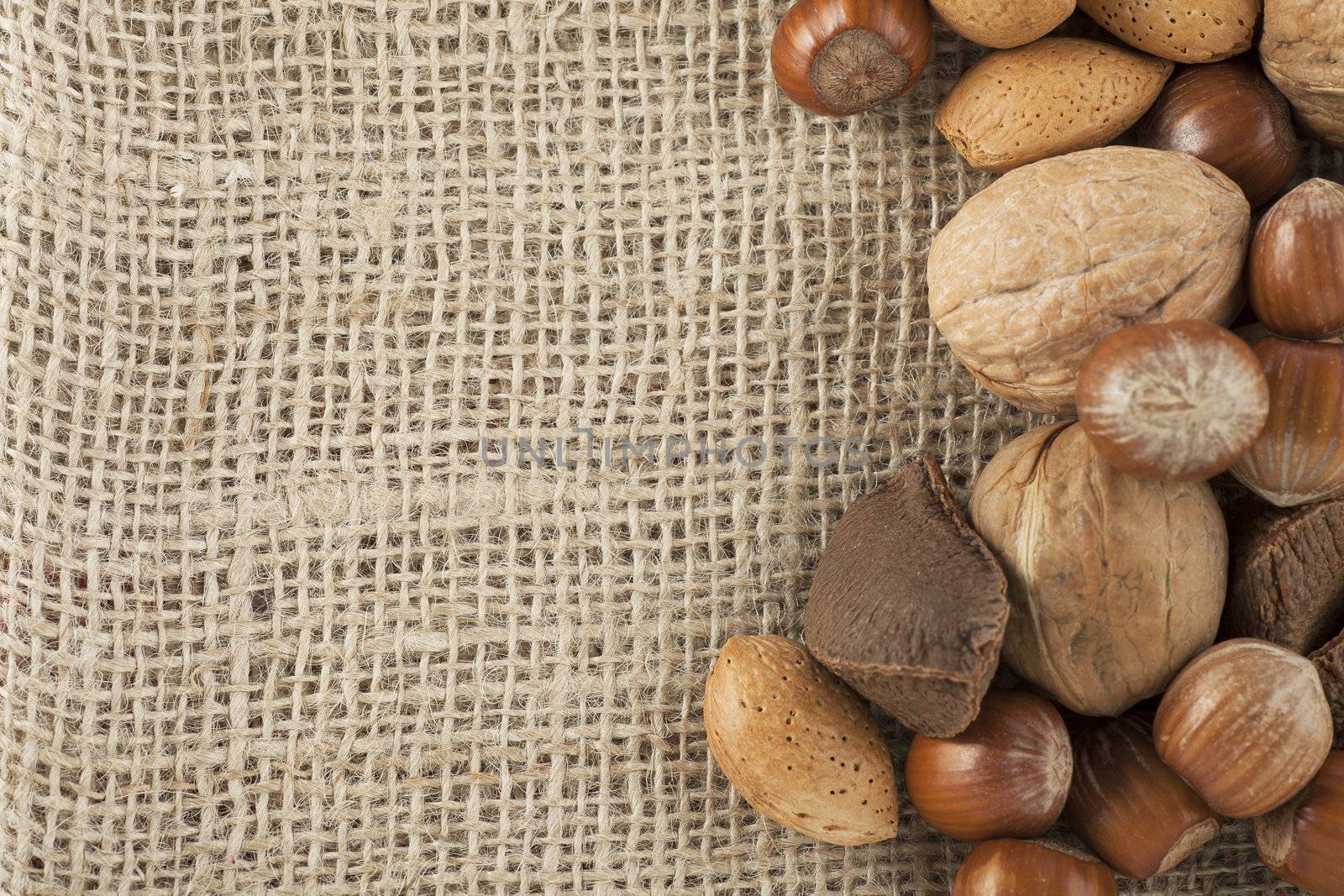 Whole unshelled hazelnuts, walnuts, almonds and brazilnuts  on burlap sack with copy space