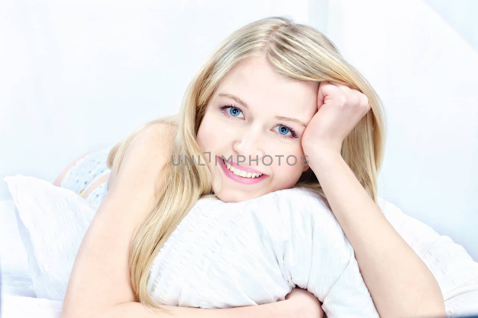 Cute blond woman on pillow in bedroom