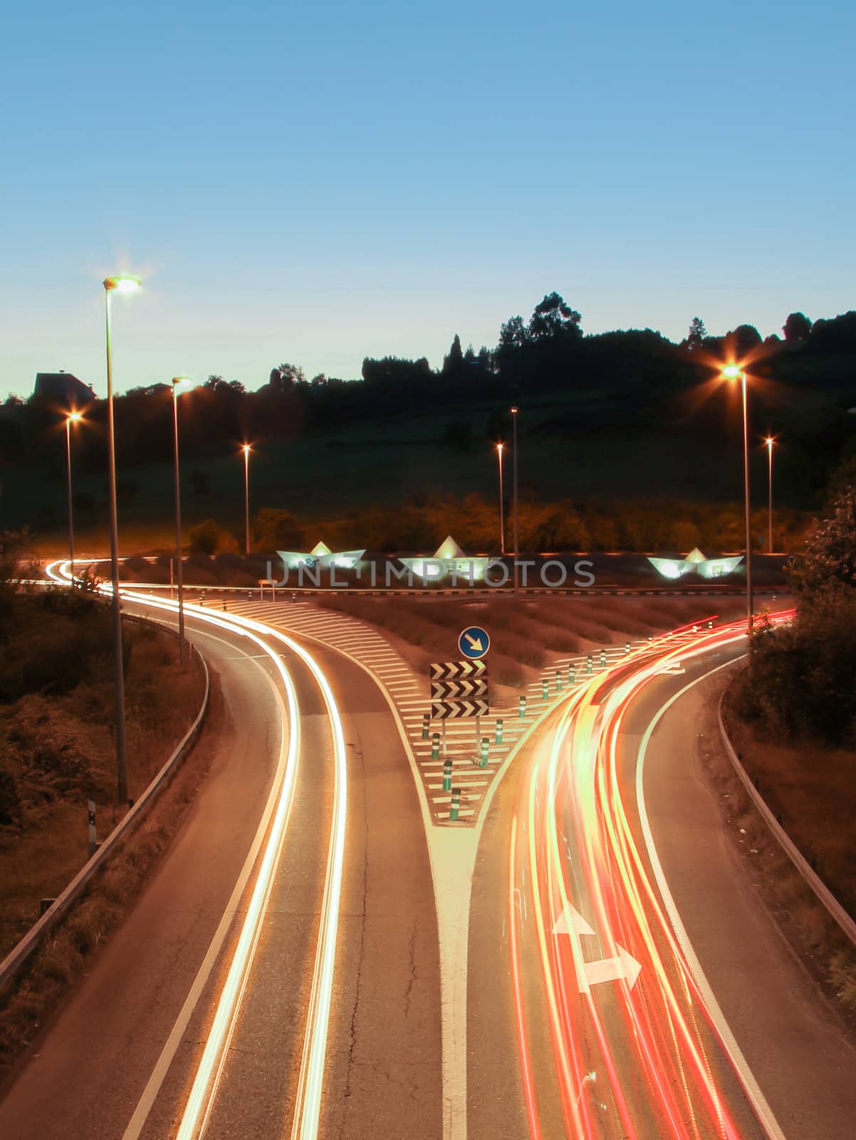 Car light trails on the road and paper boats in a roundabout by doble.d