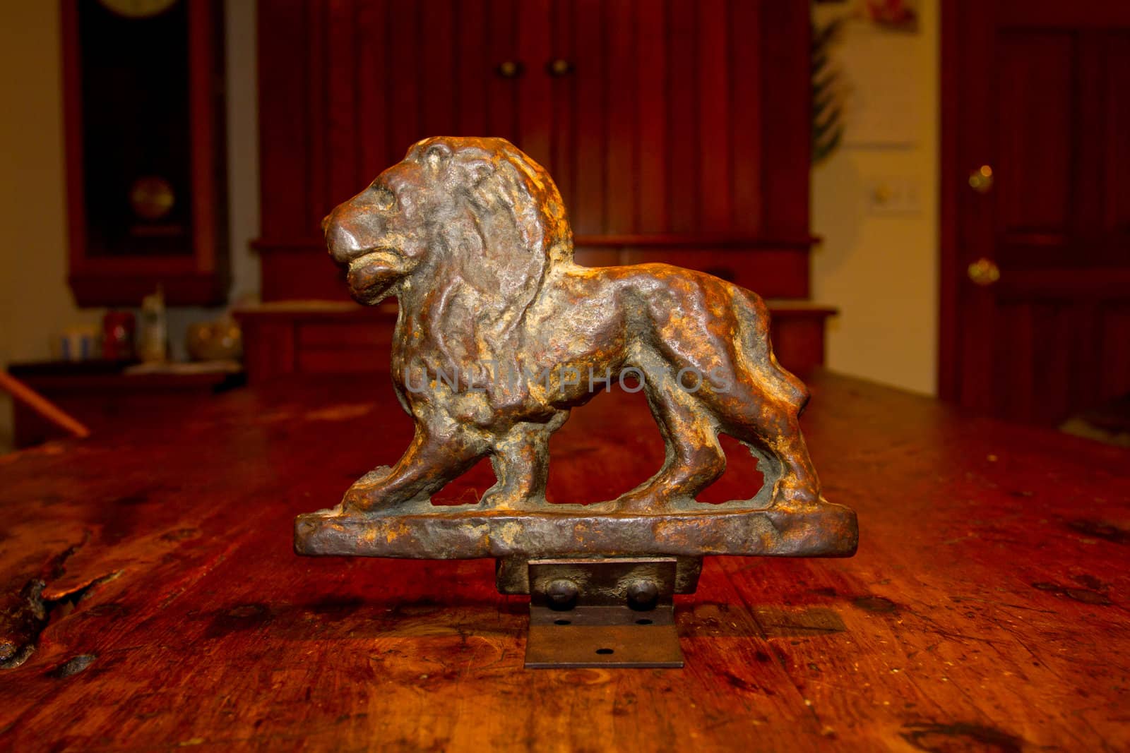 An antique bronze lion statue photographed on an old wooden table.