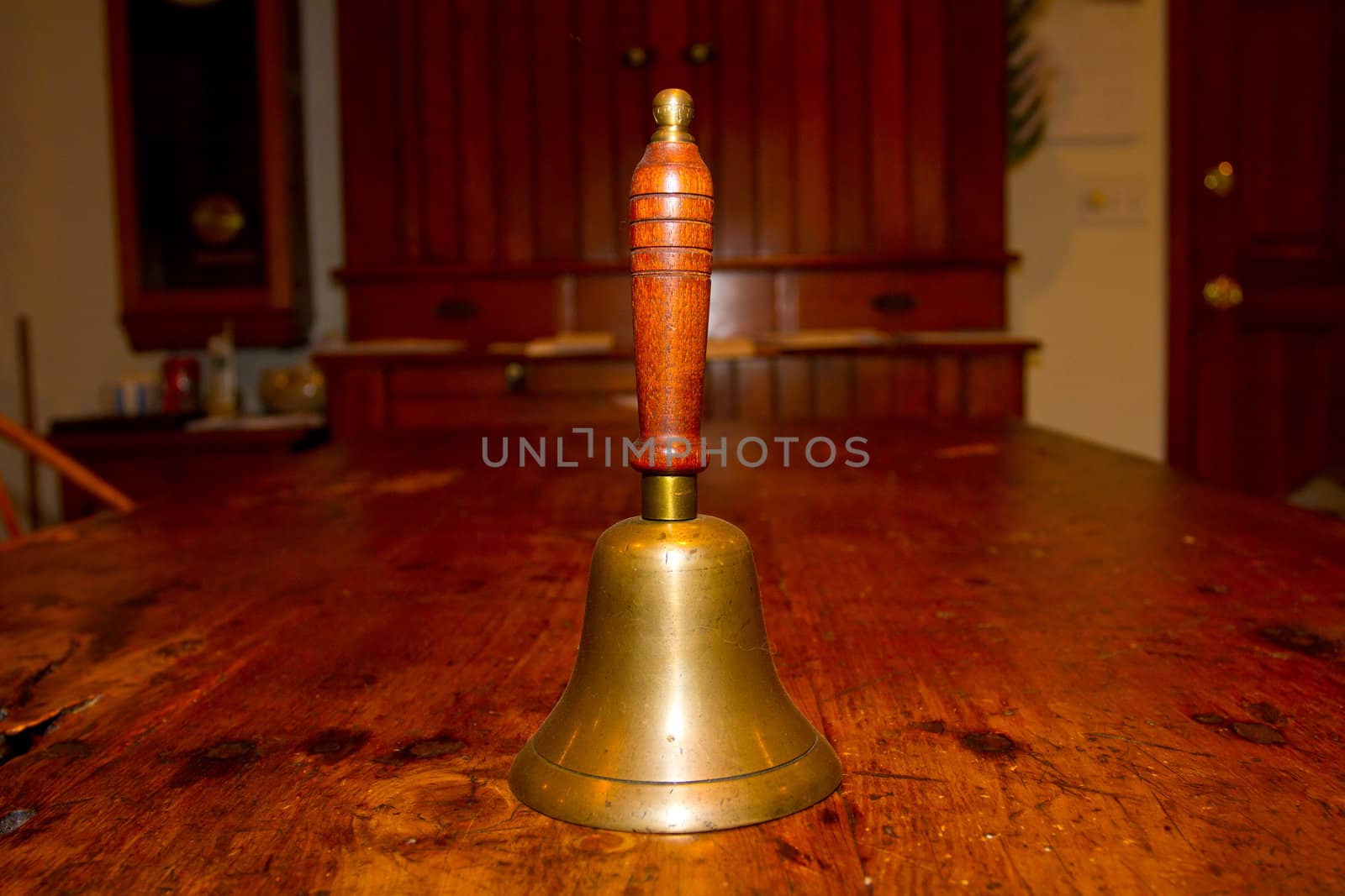 An old bell for ringing photographed on a vintage antique wooden table.