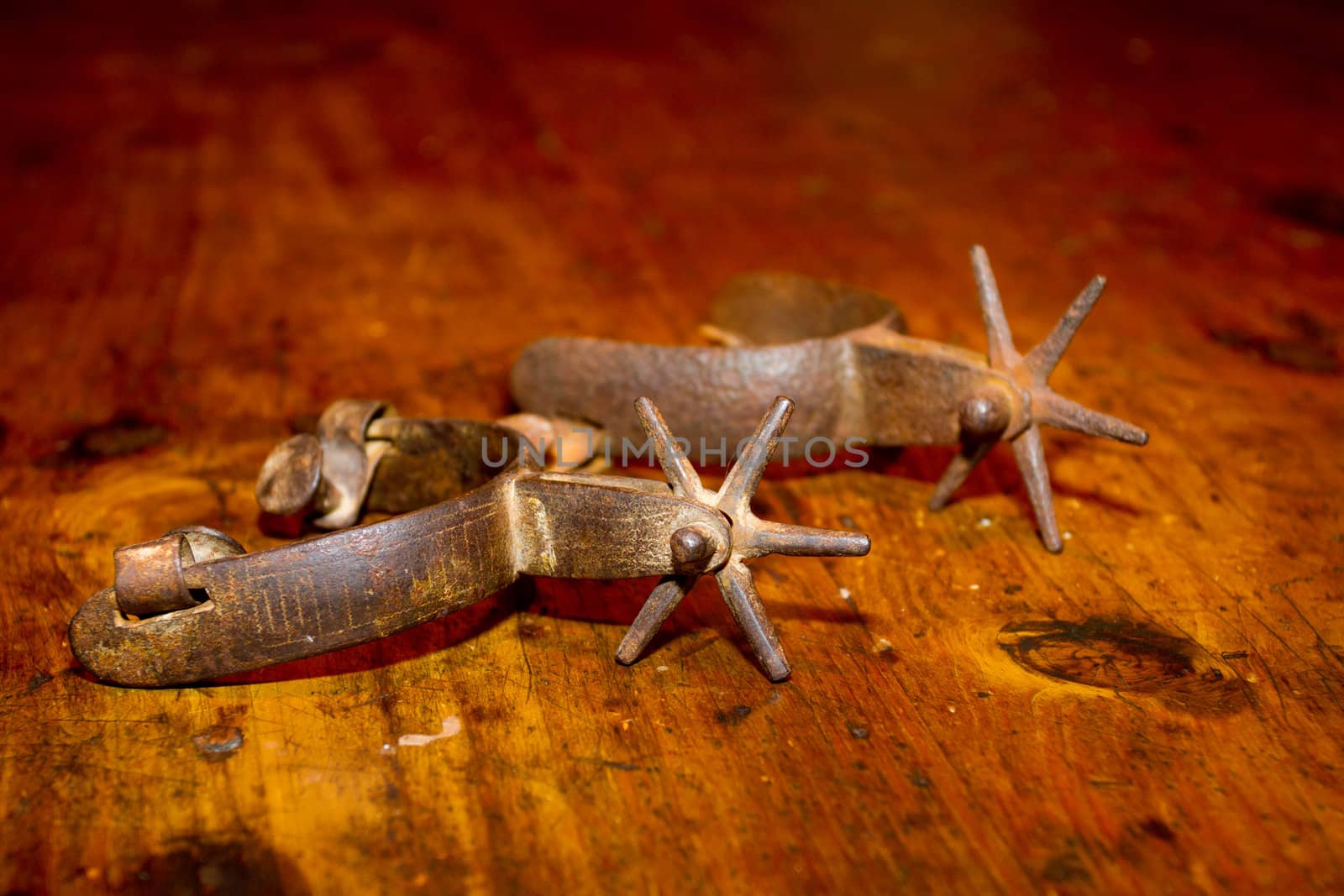 A set of old antique metal stirrups photographed on a wooden dining table.