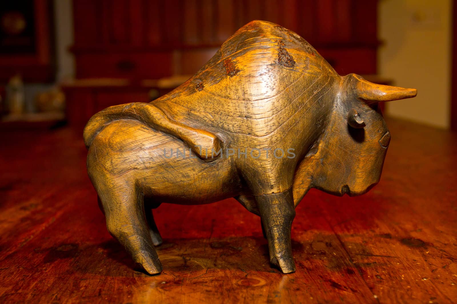 A hand carved wooden bull or buffalo statue on an antique wooden table.