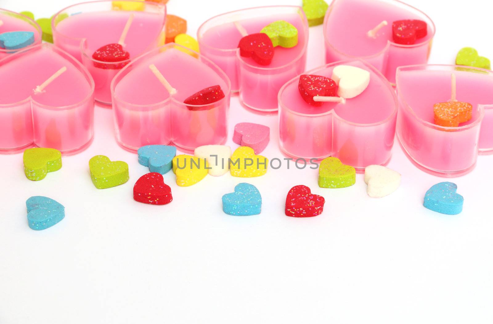 Valentine pink candles in form of heart with some small decorated hearts