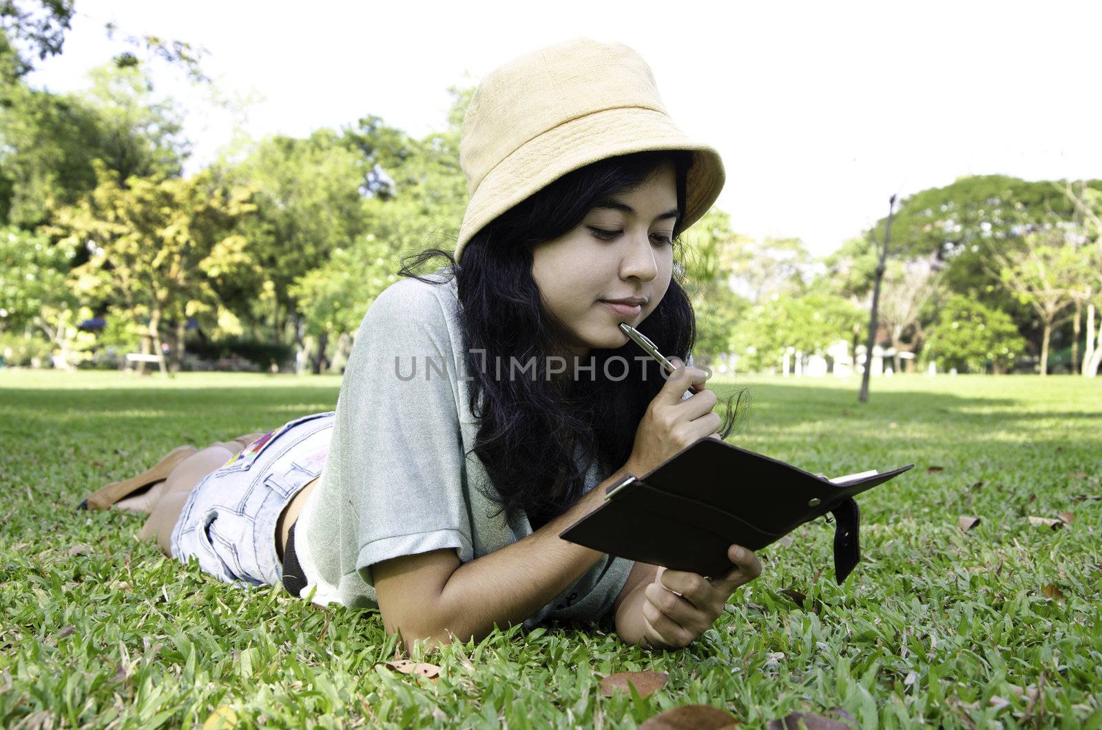 Asian woman laying on grass and thinking in park 