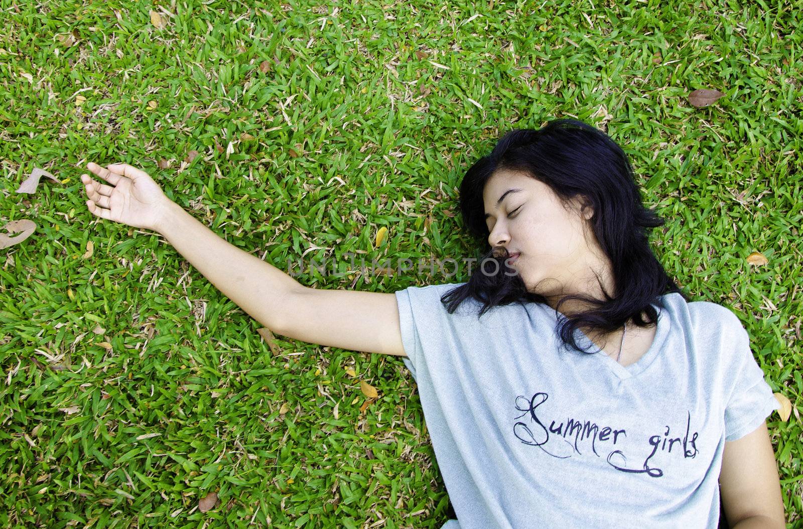 Young beautiful asian laying on the grass, in the park
