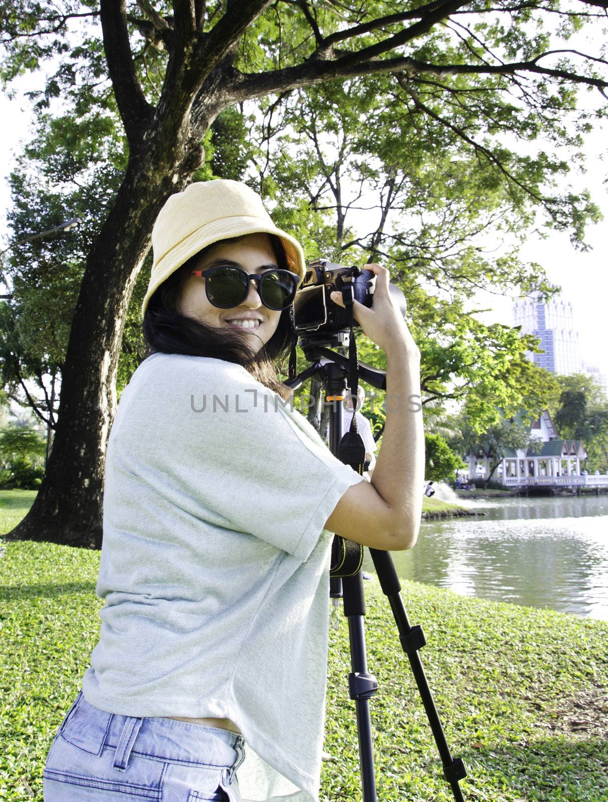 Beautiful smiling asian girl with camera on nature. 