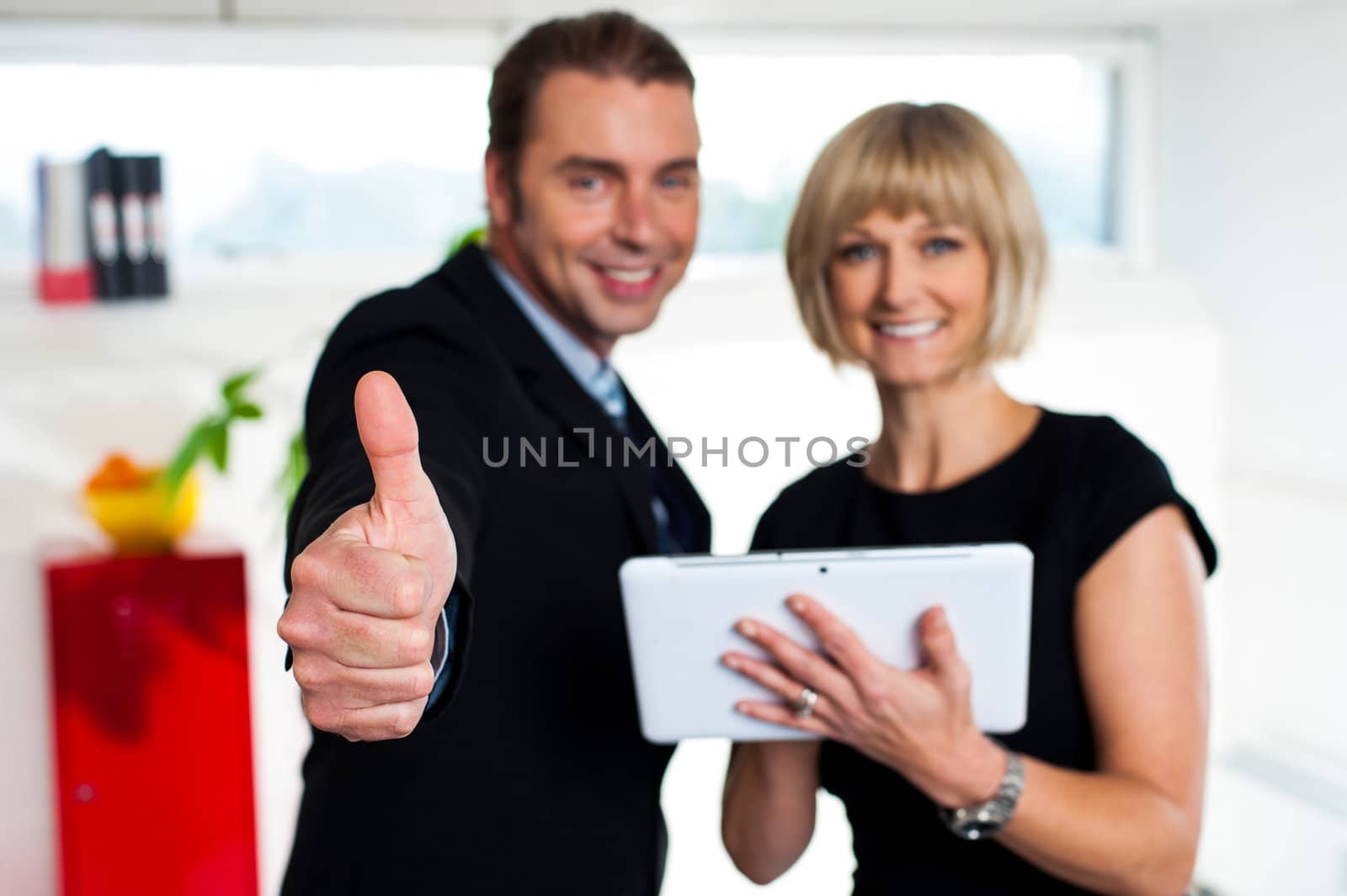 Secretary with a tablet posing with her successful boss by stockyimages
