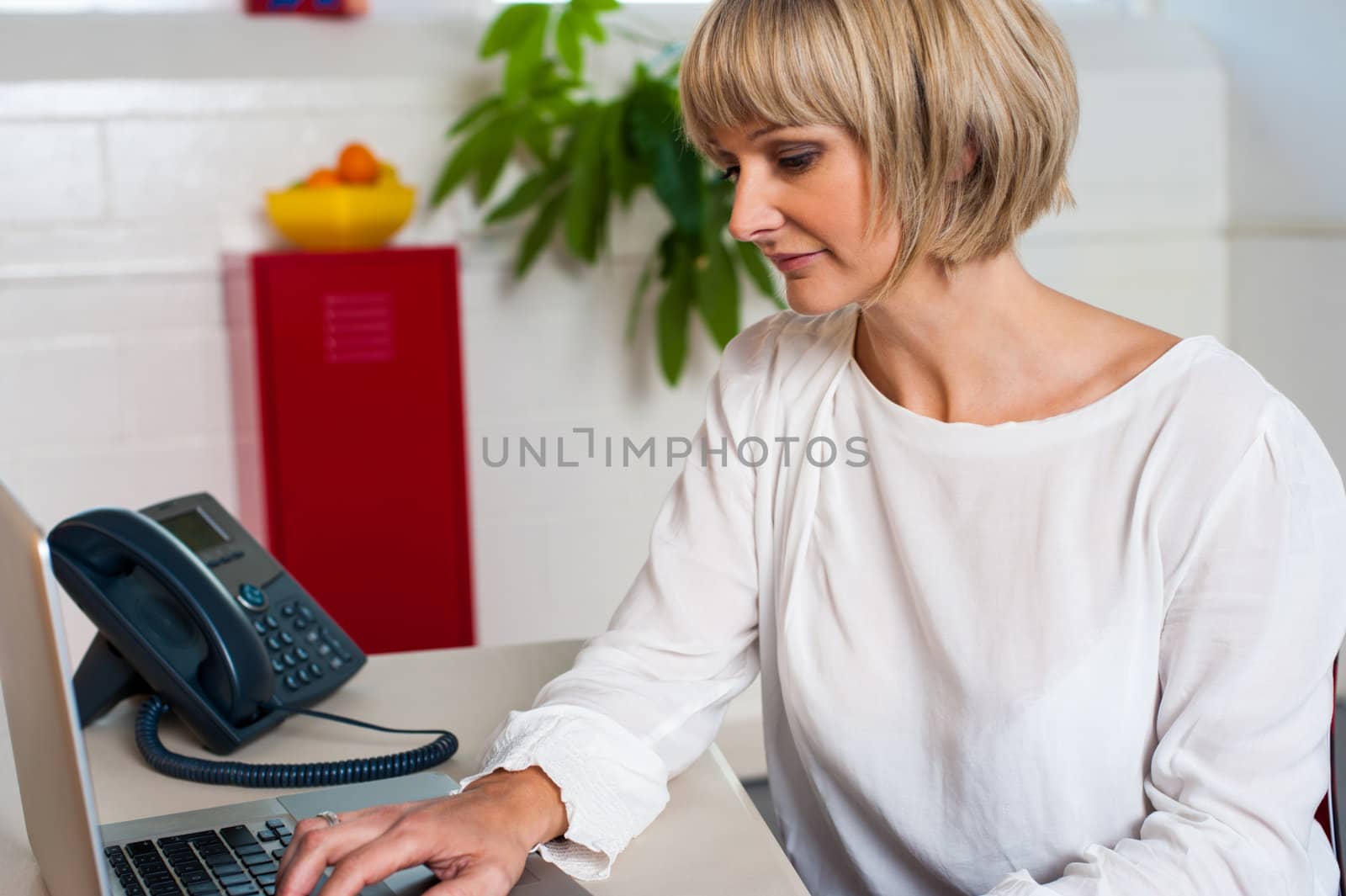 Expressionless female working on a laptop by stockyimages