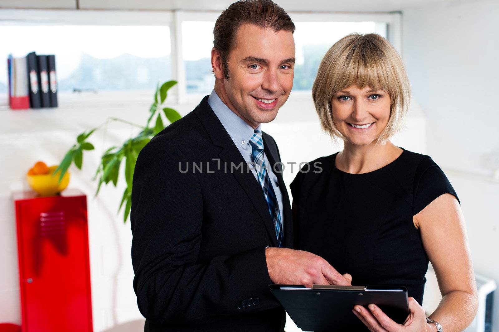 Female secretary holding clipboard and reviewing weekly schedule with her boss.