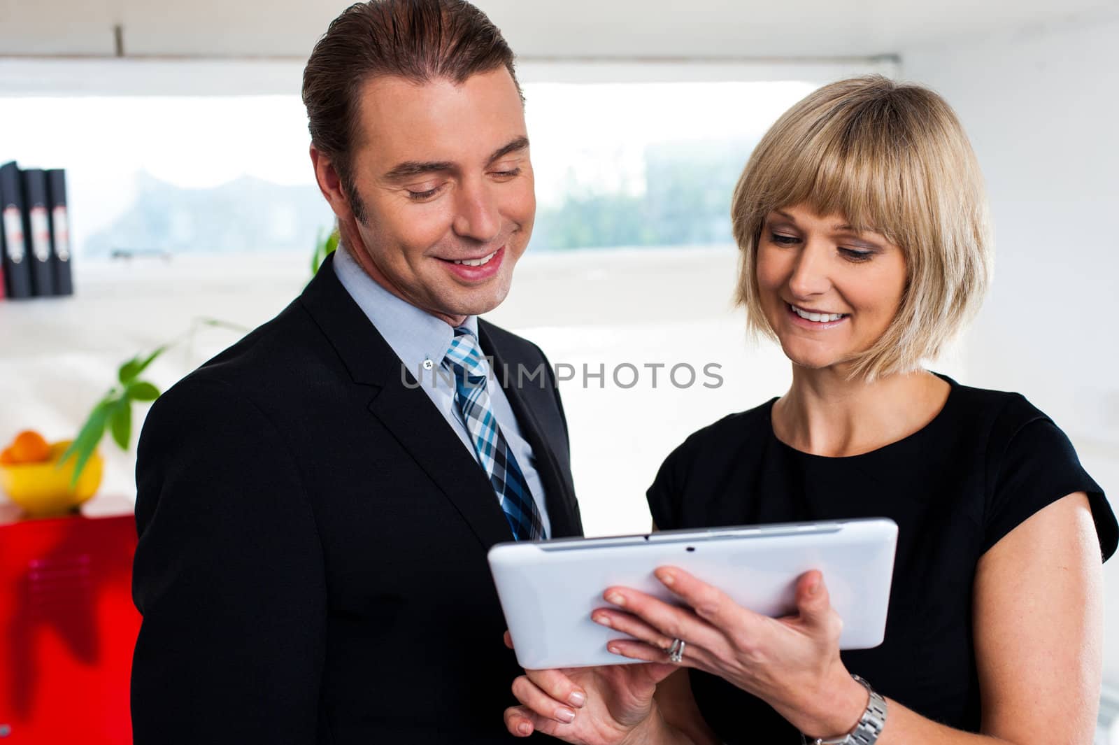 Female secretary showing appointments to boss saved on tablet device by stockyimages