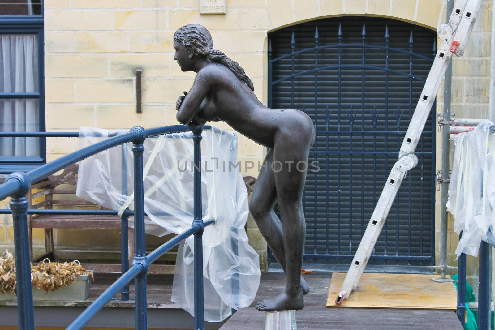Statue of a naked girl leaning on the railing of the bridge