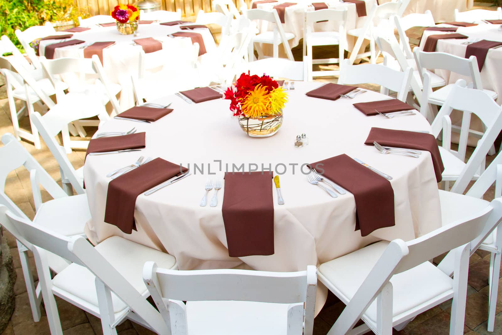 Place settings, tables, and chairs are empty before the guests arrive at a wedding reception.