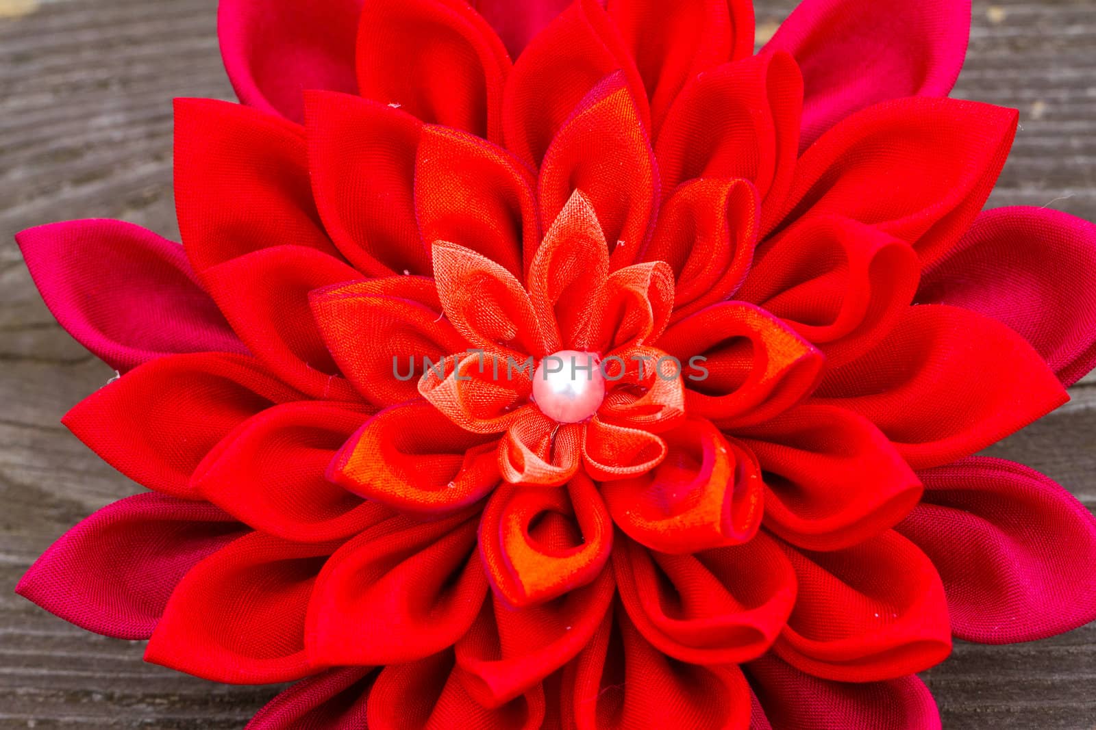 A bright red flower sewn from fabric at a wedding.