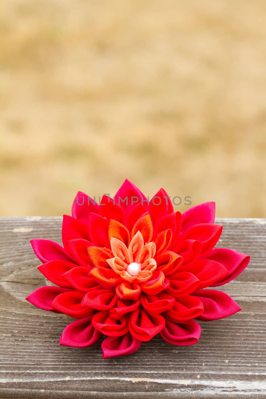 A bright red flower sewn from fabric at a wedding.