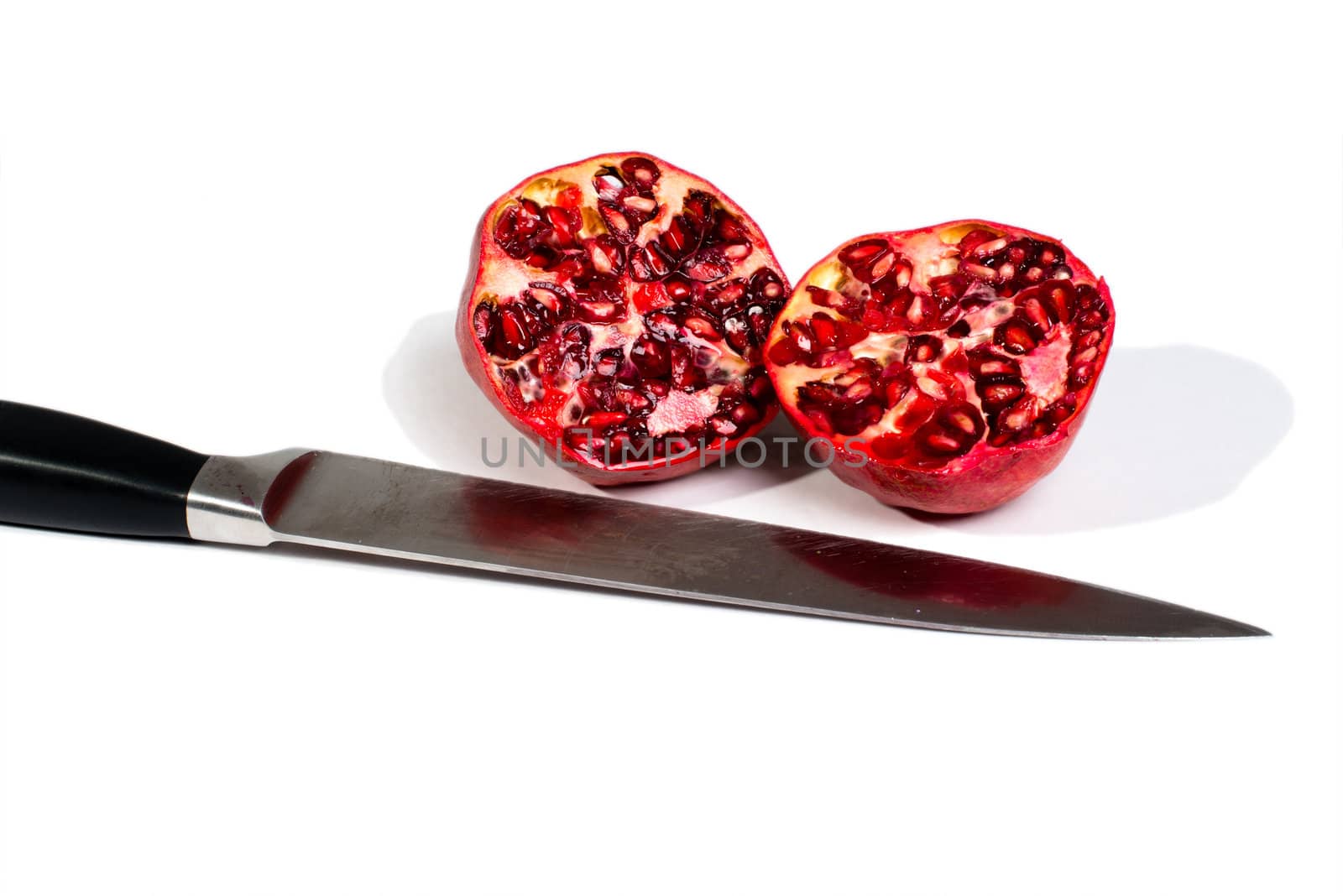 Pomegranate halves with knife isolated on a white background