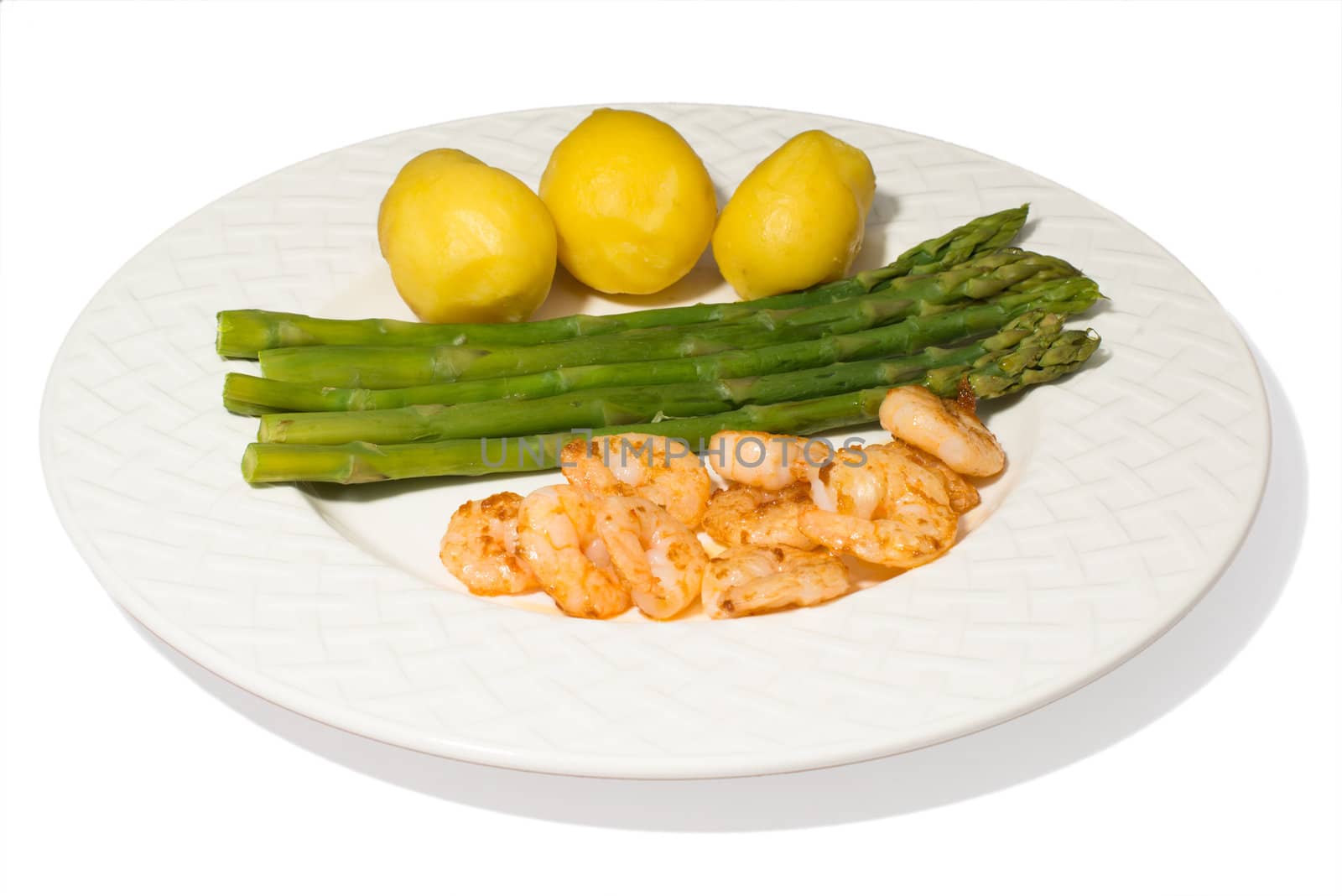 a plate with asparagus, shrimps and potatoes isolated on a white background