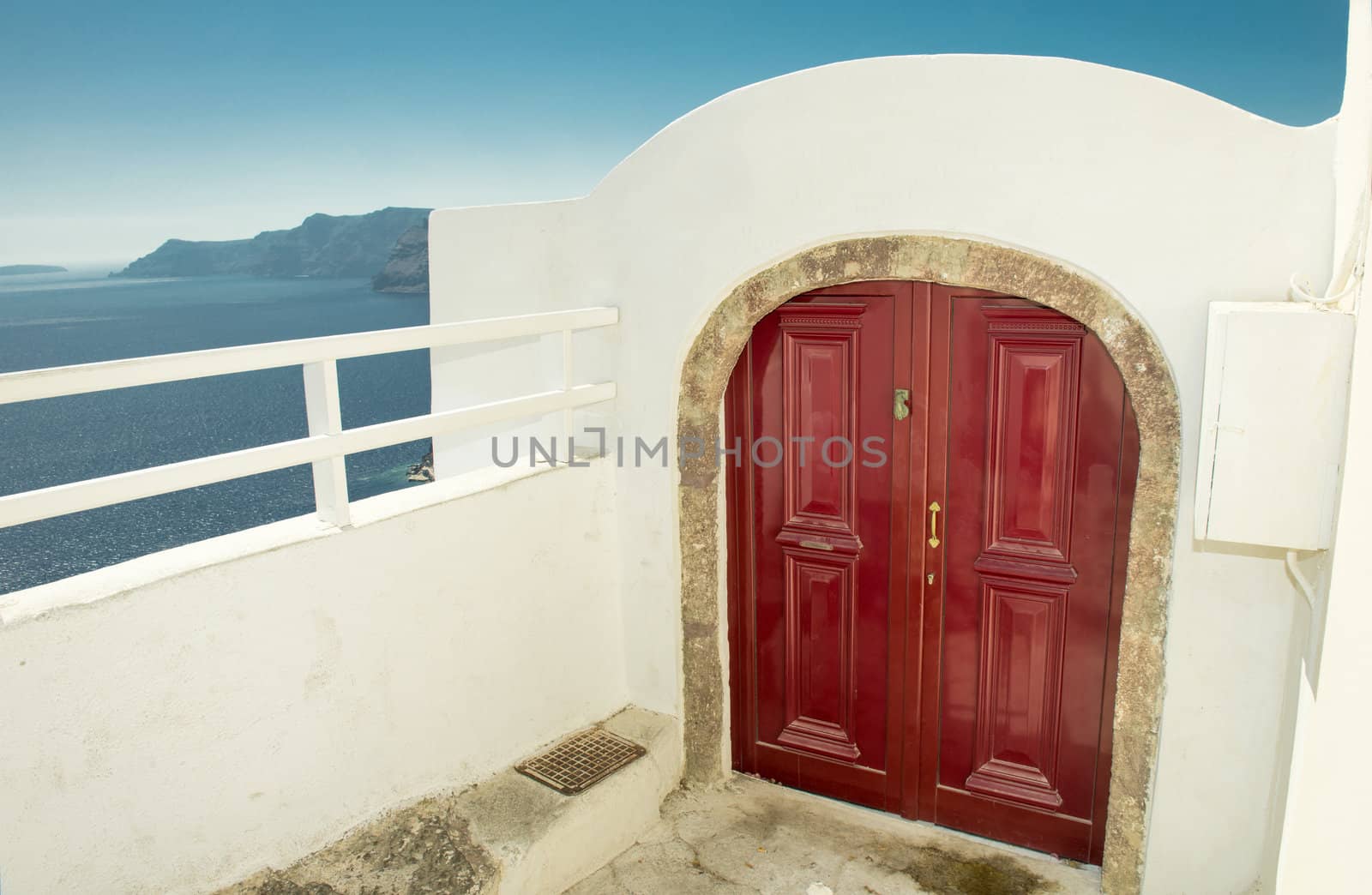 Exterior of appartment and red woden door in Oia, Santorini, Greece.