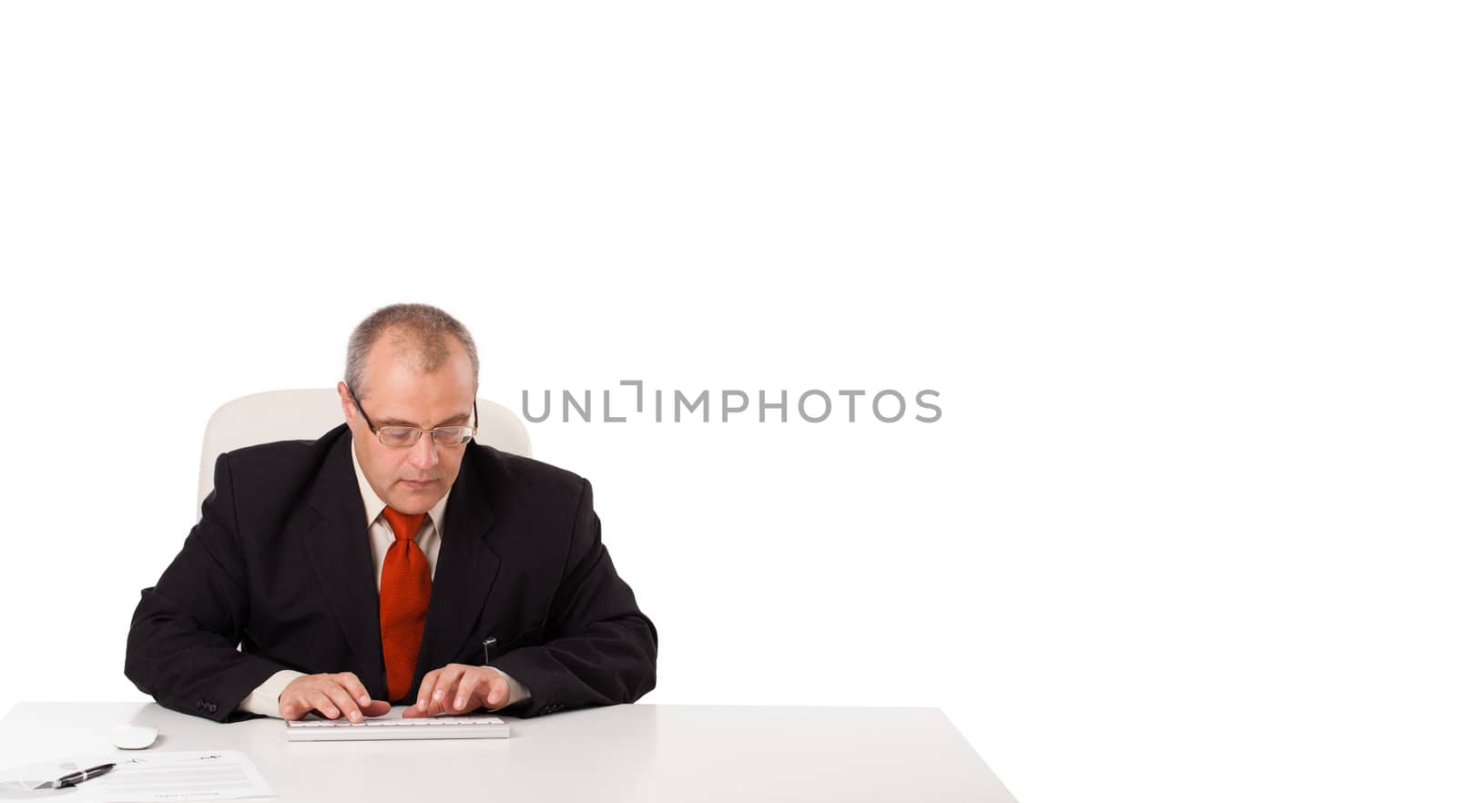 businessman sitting at desk and typing on keyboard with copy scape, isolated on white