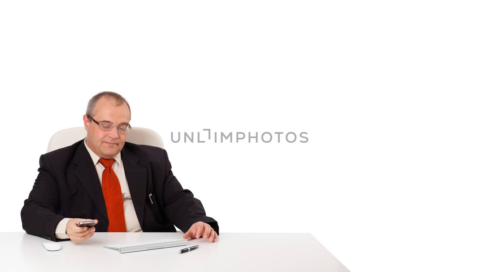 businessman sitting at desk and holding a mobilephone with copys pace, isolated on white