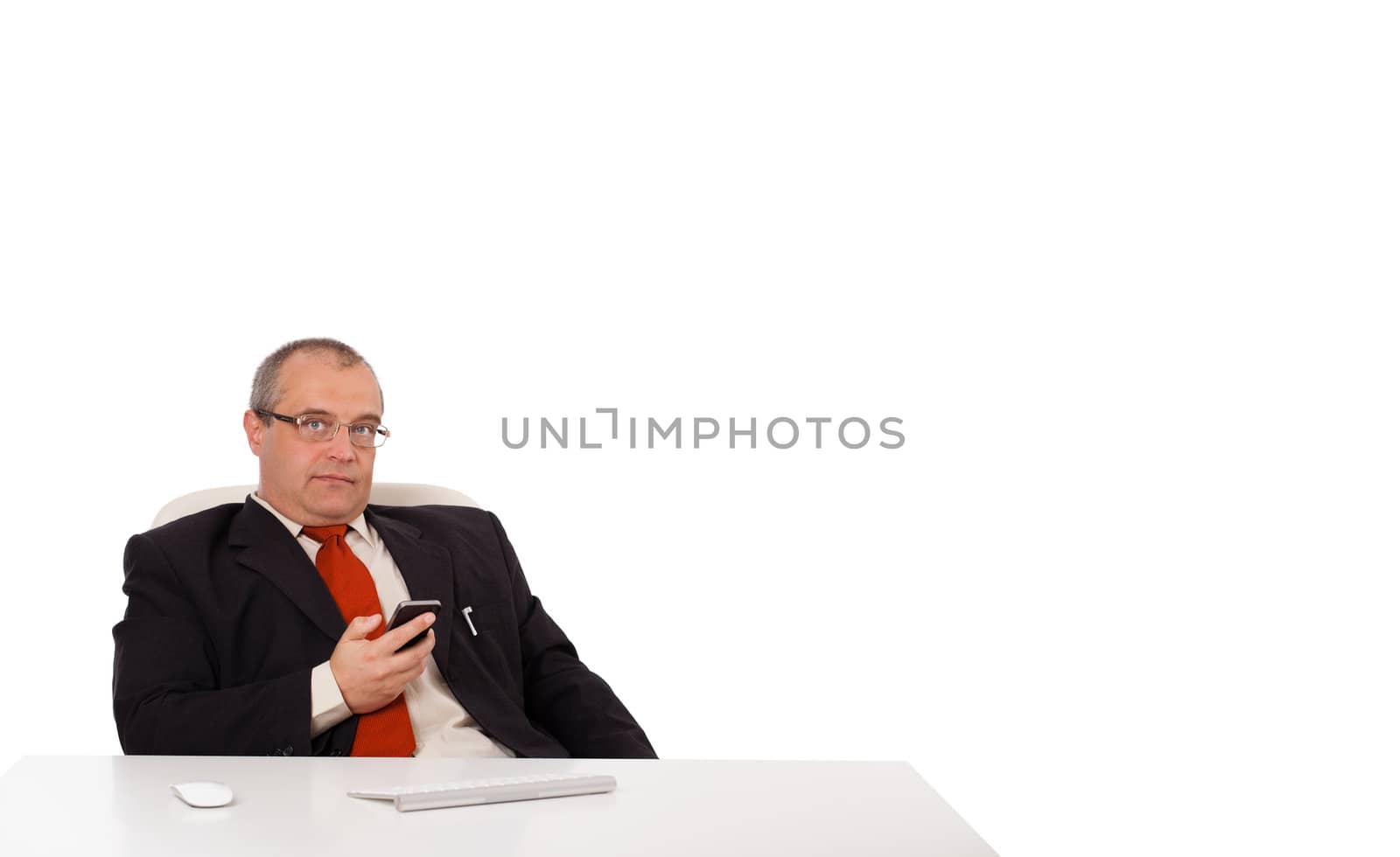 businessman sitting at desk and holding a mobilephone with copys pace, isolated on white