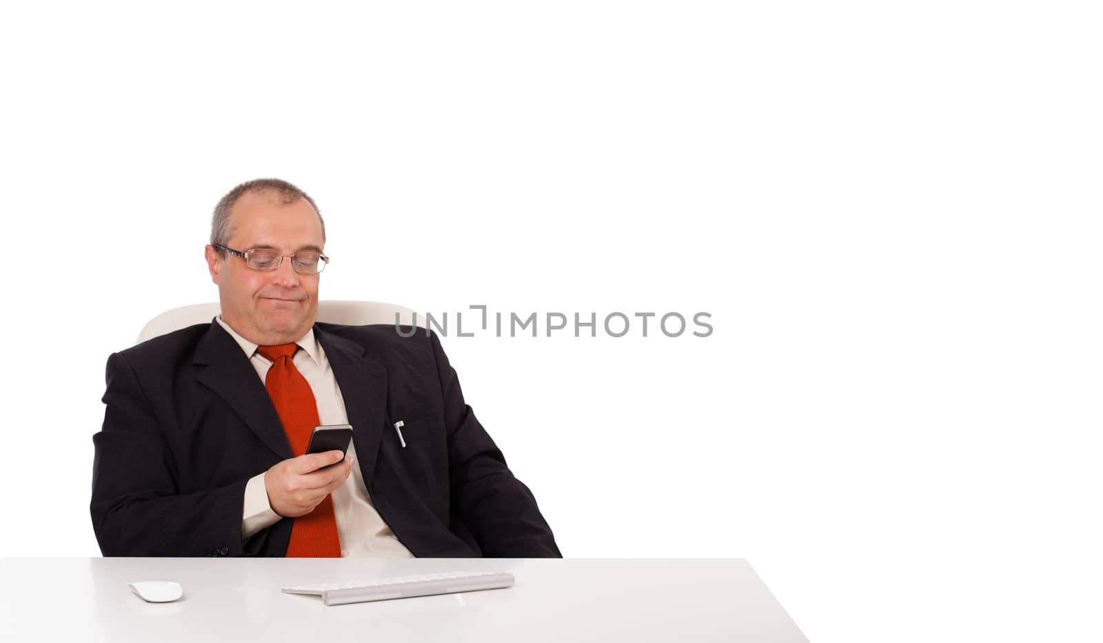 businessman sitting at desk and holding a mobilephone with copys pace, isolated on white