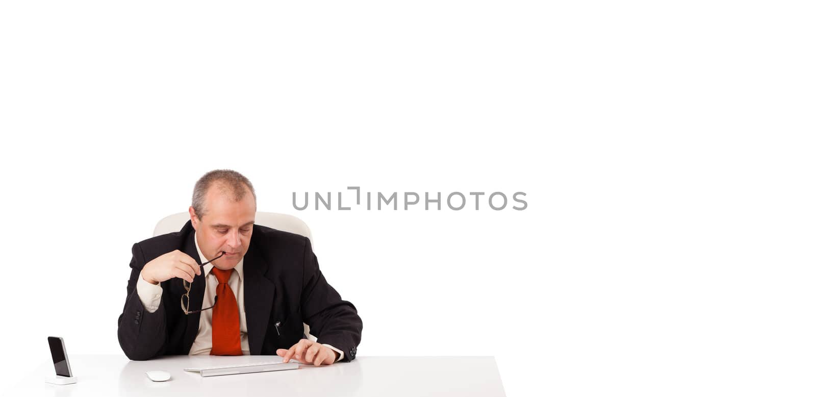 businessman sitting at desk and typing on keyboard with copy scape, isolated on white