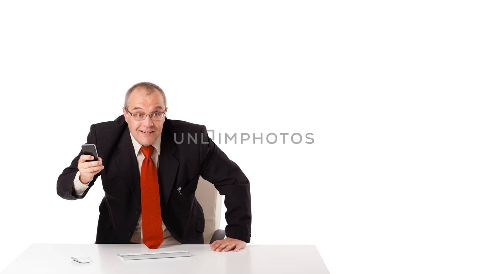 businessman sitting at desk and holding a mobilephone with copys pace, isolated on white