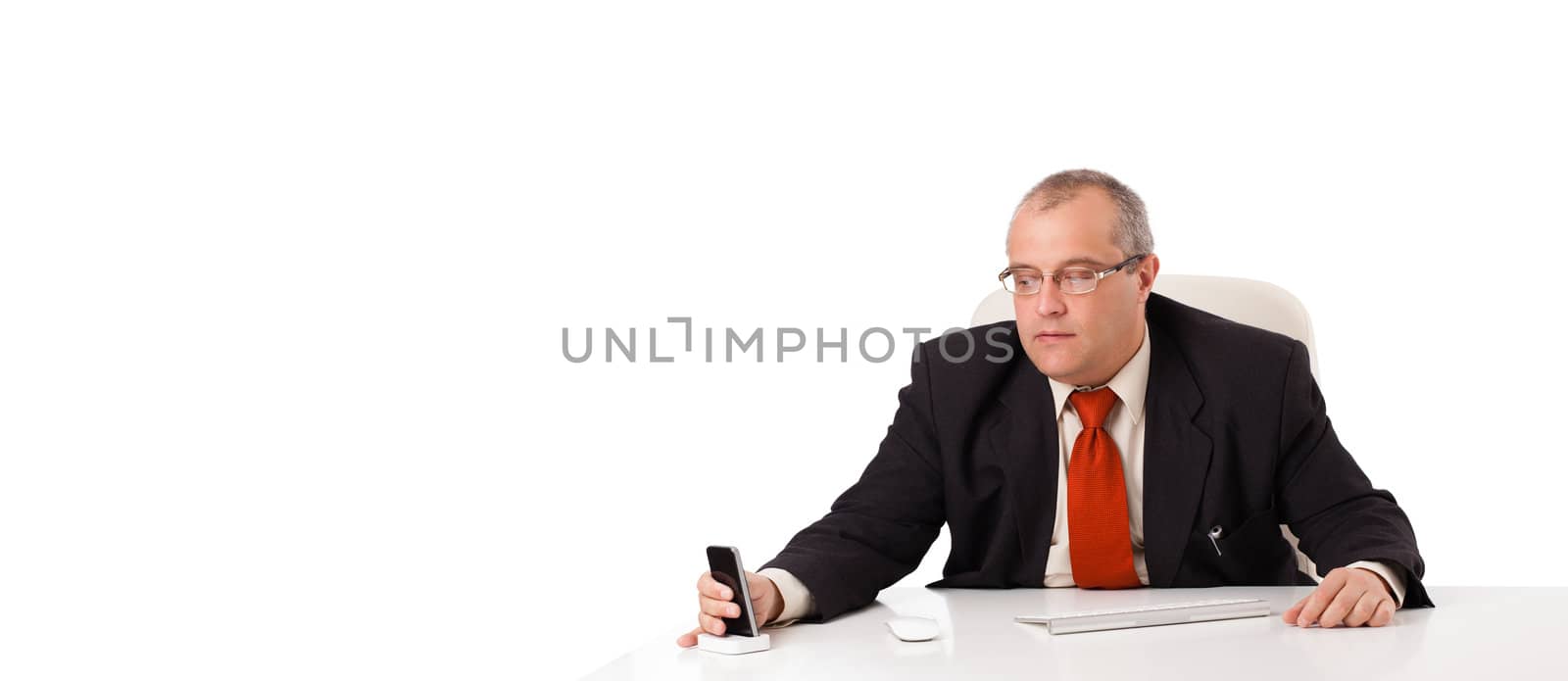 businessman sitting at desk and holding a mobilephone with copys pace, isolated on white