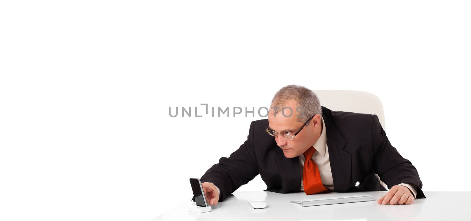 businessman sitting at desk and holding a mobilephone with copys pace, isolated on white